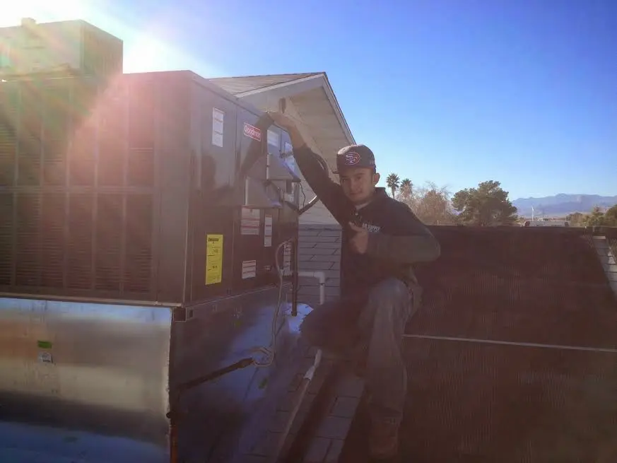 HVAC technician performing AC Tune-Up on a rooftop unit in Eliot